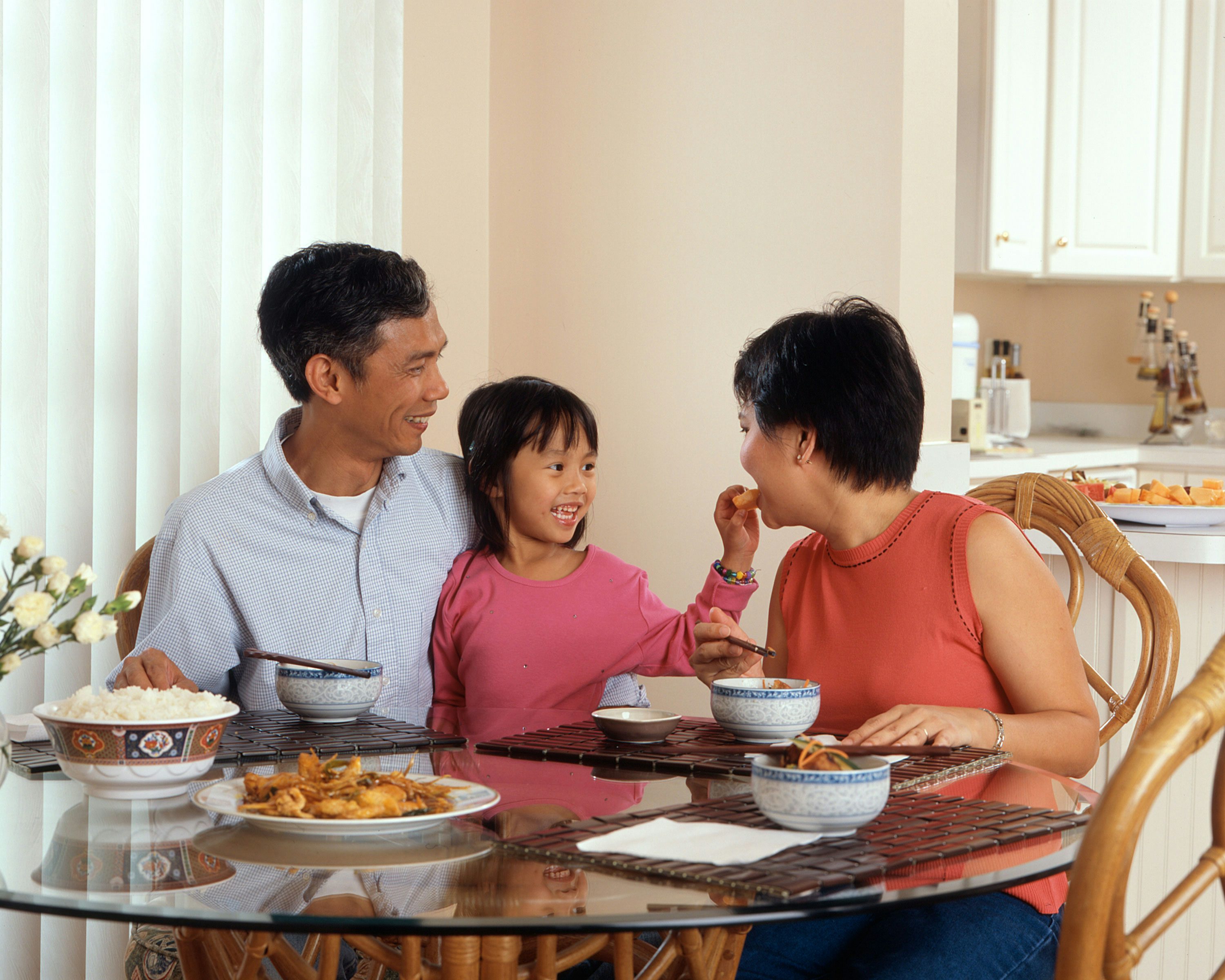 A person at a kitchen island checking a fasting timer while setting out water glasses before dinner
